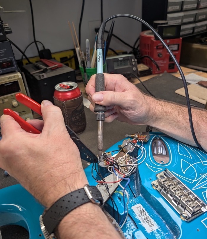 Soldering a Stratocaster control harness with an iron at the bench
