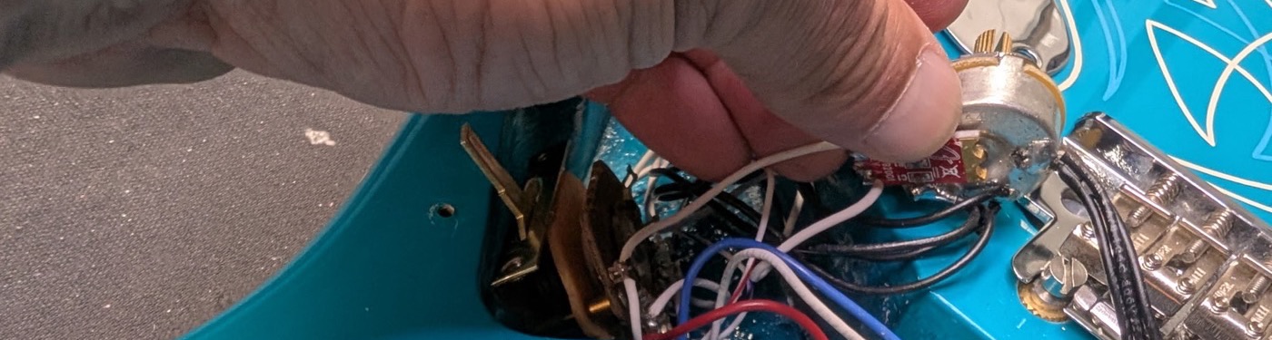 Pickguard lifted off a Stratocaster body exposing the control cavity wiring